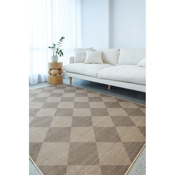 Living room with a checkered rug, white sofa, and small table with plants.