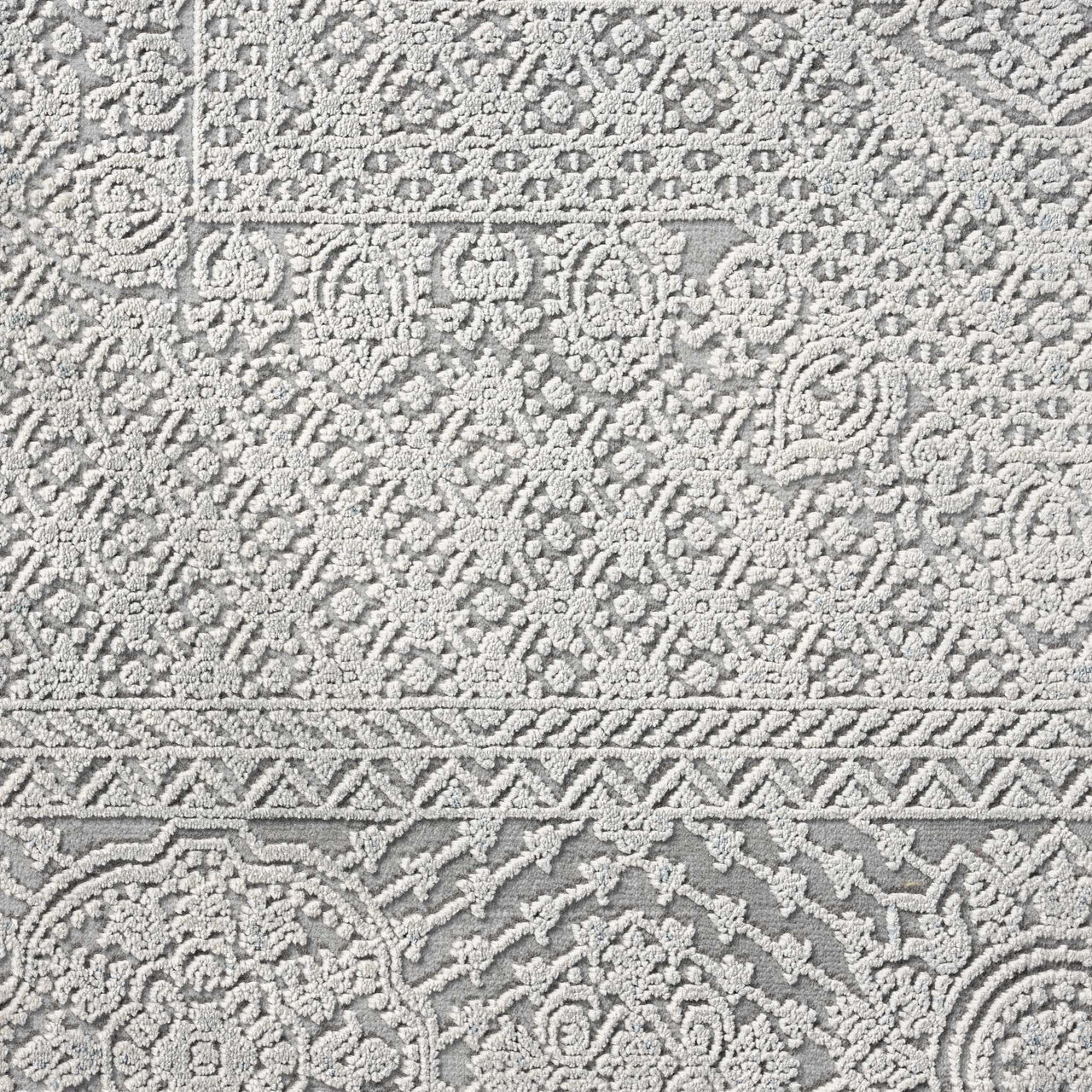 Grey runner rug with intricate raised abstract patterns and textured border detailing.