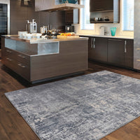Grey multi-colored abstract rug with textured design on dark wood floor in modern kitchen.