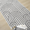 Grey flatweave runner rug with minimalist geometric arch pattern on light wood floor.
