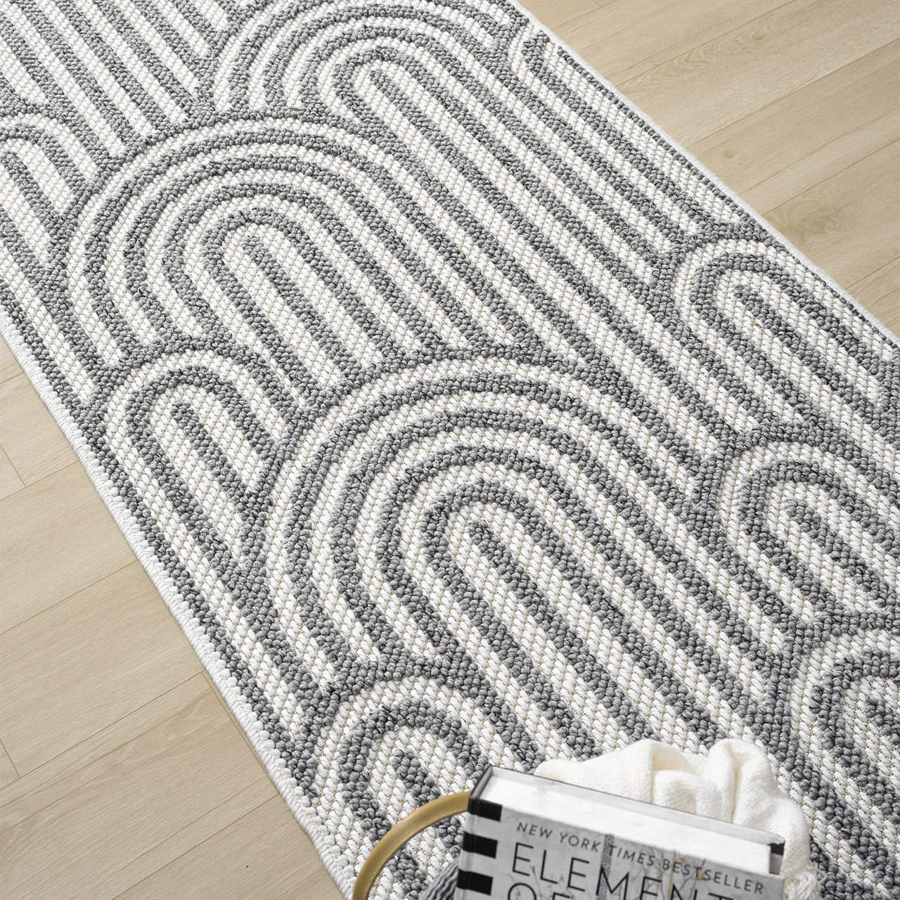 Grey flatweave runner rug with minimalist geometric arch pattern on light wood floor.