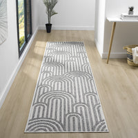 Grey flatweave runner rug with repeating arch geometric pattern in light and dark tones on light wood floor.