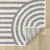 Grey flatweave rug with bold curved and straight geometric lines on light wood floor.
