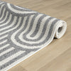Rolled grey and white flatweave runner rug with curved geometric stripes on light wood floor.