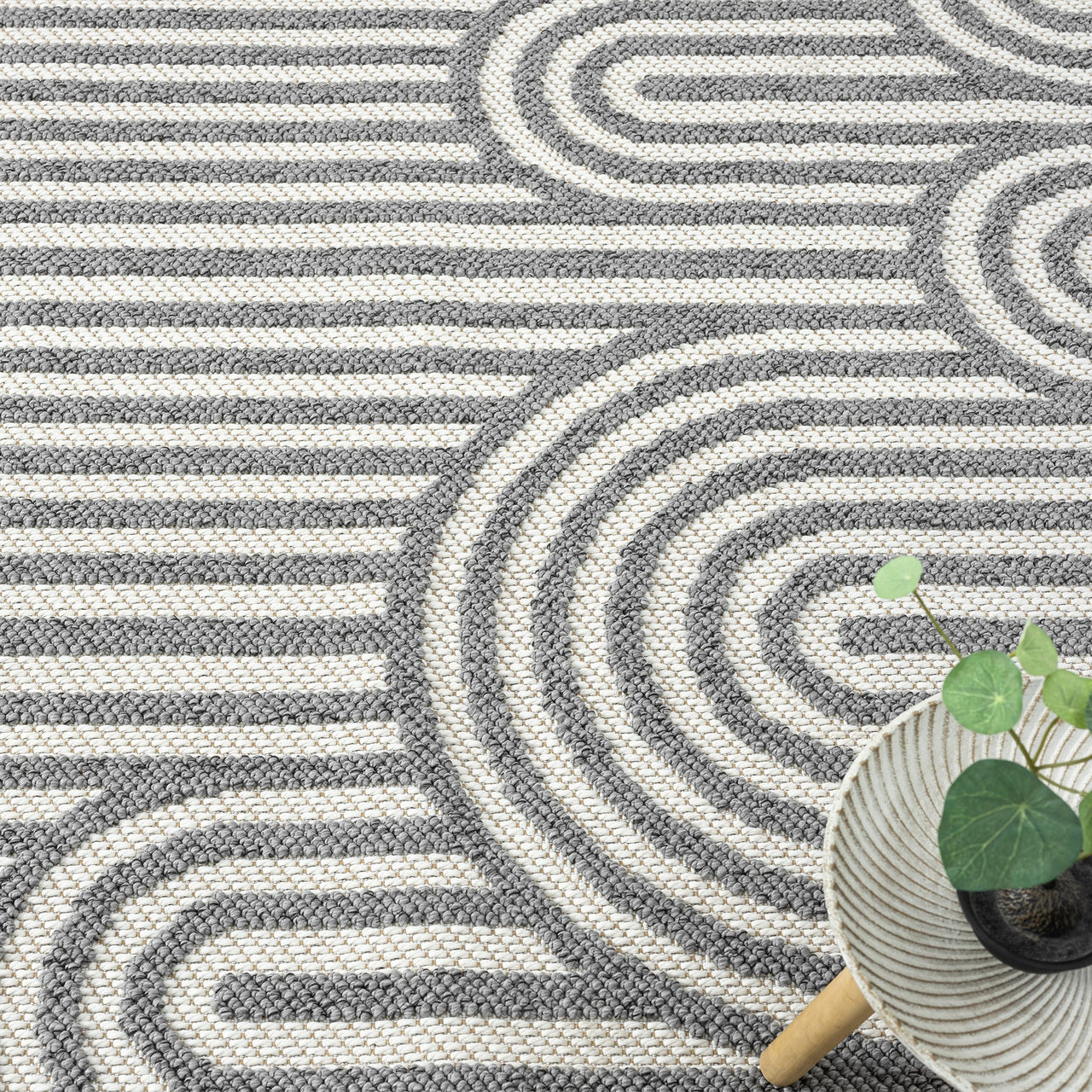 Grey flatweave rug with concentric arches and horizontal stripe geometric pattern.