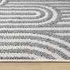 Grey flatweave rug with textured geometric arch pattern on a wooden floor.