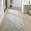 Grey flatweave runner rug with geometric diamond pattern on light wood floor.