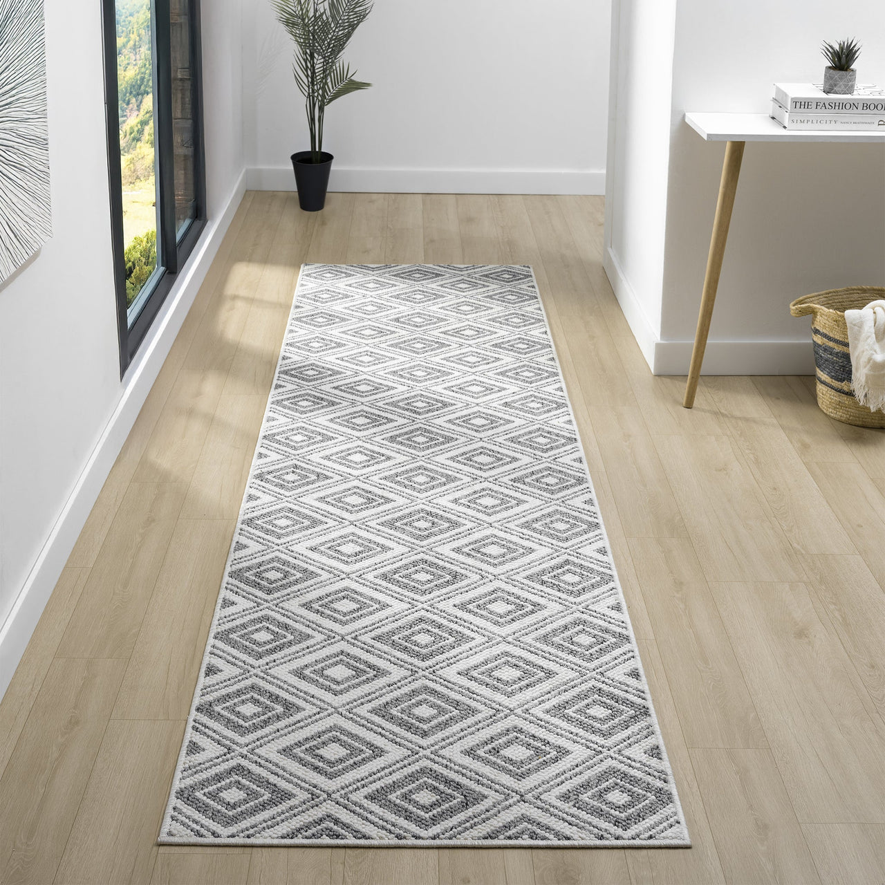Grey flatweave runner rug with geometric diamond pattern on light wood floor.