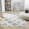Grey flatweave rug with white and dark grey geometric diamond pattern on light wood floor.