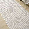 Cream flatweave runner rug with textured geometric arches on light wooden floor.