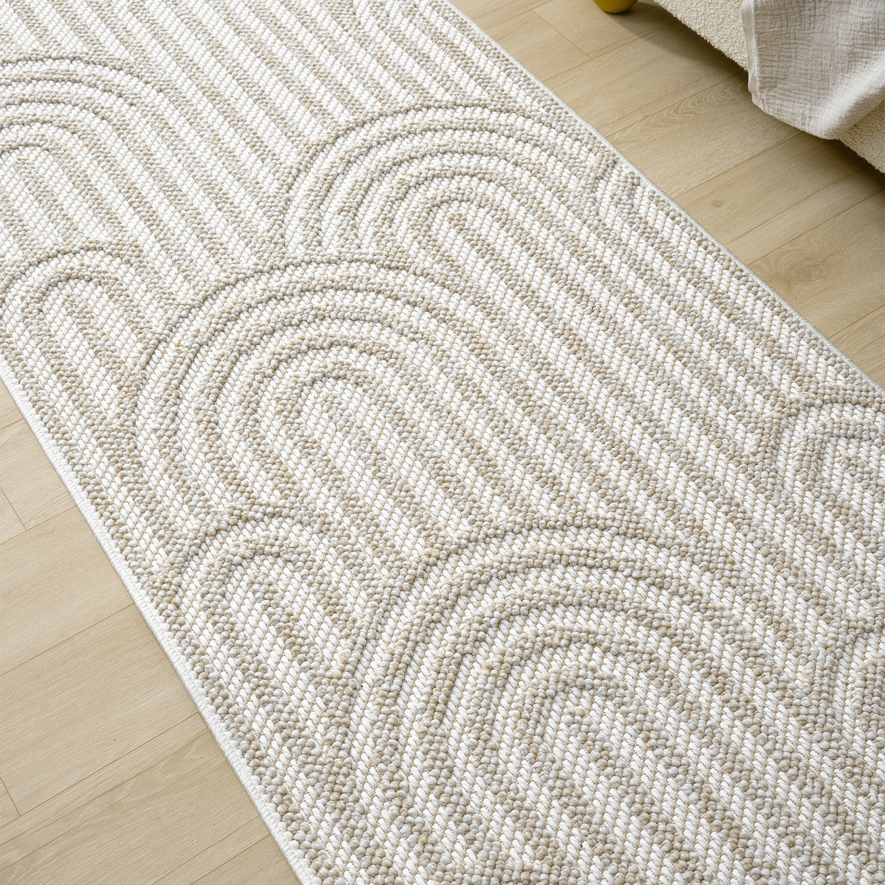 Cream flatweave runner rug with textured geometric arches on light wooden floor.