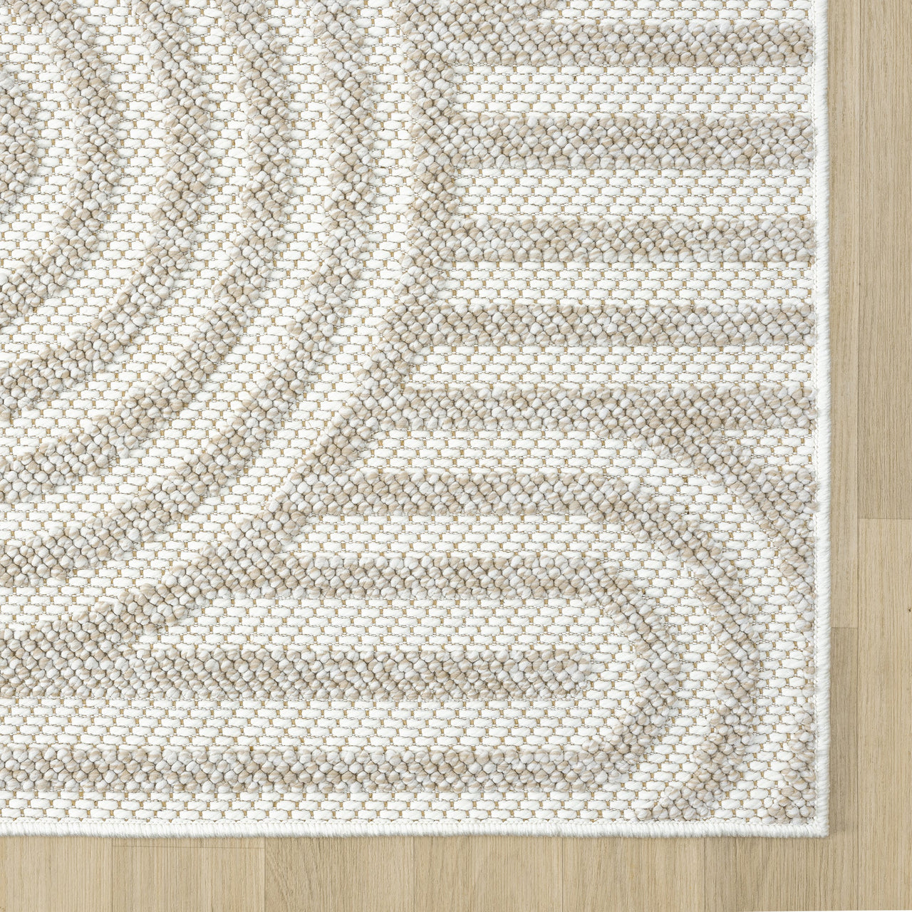 Cream flatweave rug with subtle concentric geometric pattern on light hardwood floor.