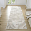 Cream flatweave runner rug with textured geometric arches pattern on light hardwood floor.
