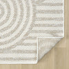Cream and beige flatweave runner rug with subtle geometric circular and linear pattern, folded corner on light wood floor.