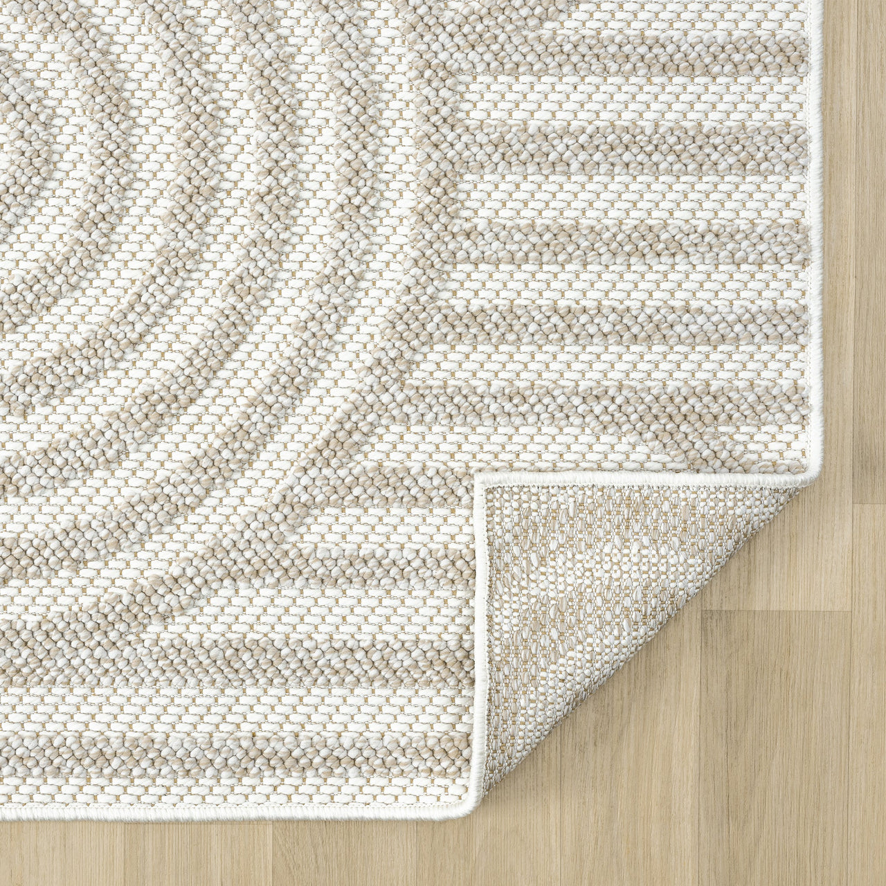 Cream and beige flatweave runner rug with subtle geometric circular and linear pattern, folded corner on light wood floor.