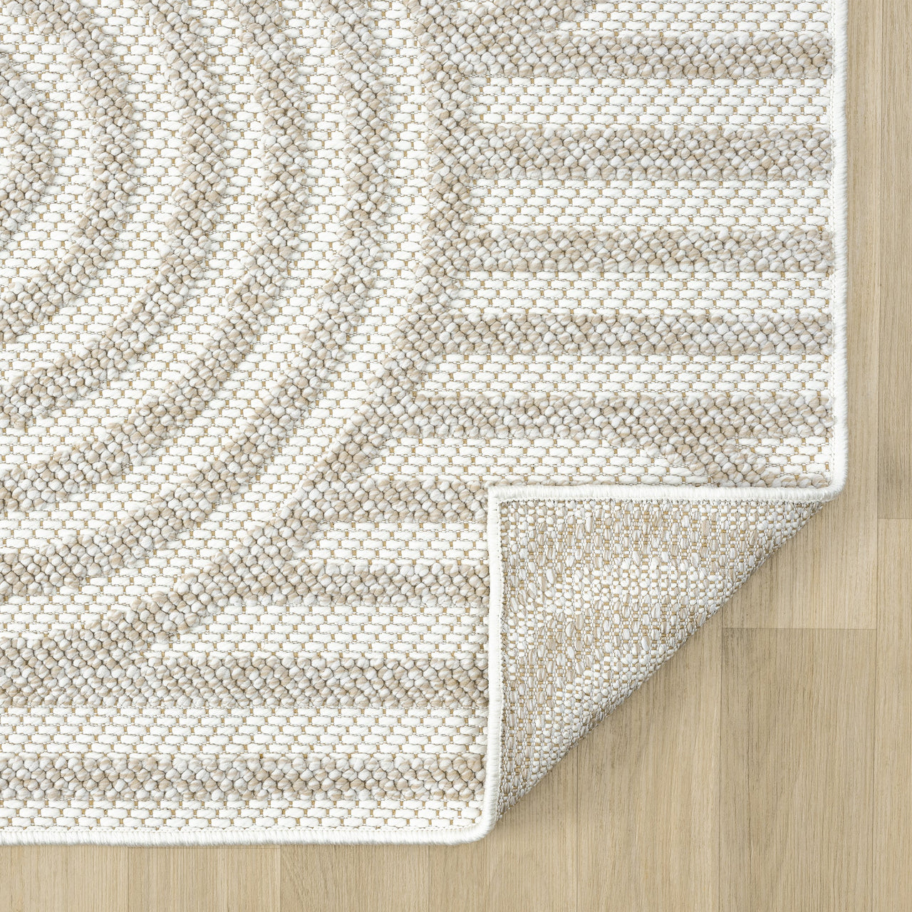 Cream flatweave rug with geometric arch and stripe pattern in beige tones on wood floor.