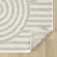 Cream flatweave rug with geometric arch and stripe pattern in beige tones on wood floor.
