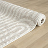 Cream and beige flatweave rug with subtle geometric arch pattern rolled on light wood floor.