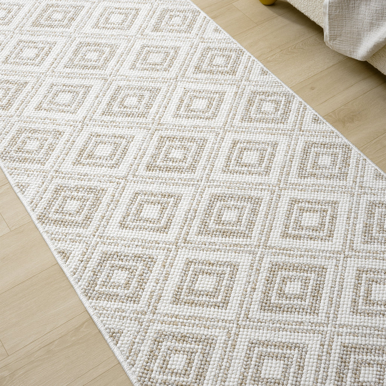 Cream flatweave runner rug with beige geometric diamond pattern on light wood floor.