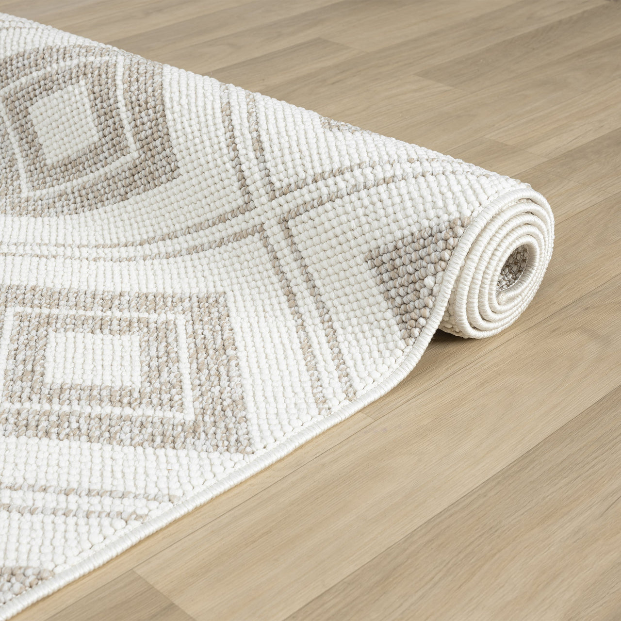 Cream flatweave rug with beige diamond geometric pattern on hardwood floor.