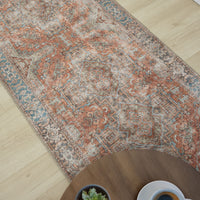 Multi-colored traditional runner rug with floral and geometric patterns in muted reds, blues, and beige tones on a flatwoven .