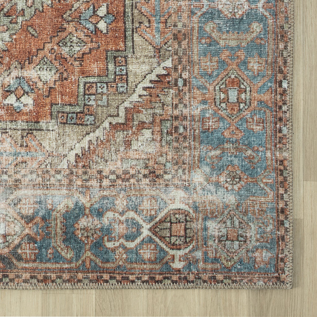 Rectangular runner rug with traditional floral motifs in muted blue, rust, and beige tones with a distressed flatweave.