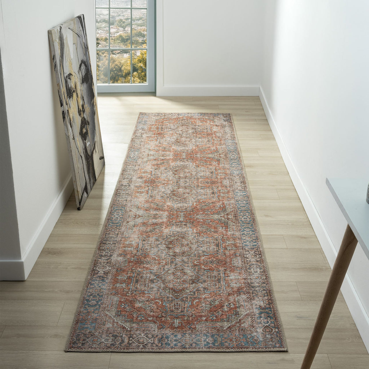 Long narrow traditional runner rug with muted multi-colored floral patterns in orange, gray, and beige tones on a distressed .