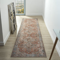 Long narrow traditional runner rug with muted multi-colored floral patterns in orange, gray, and beige tones on a distressed .