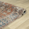 Rolled traditional runner rug with distressed floral patterns in muted blues, rusty reds, and beige tones on a flatweave.