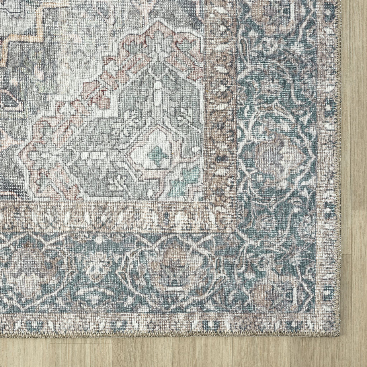 Grey traditional runner rug corner with intricate floral and geometric patterns in muted blue, beige, and rust tones,.