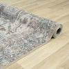 Rolled grey runner rug with distressed floral traditional patterns on light wood floor.