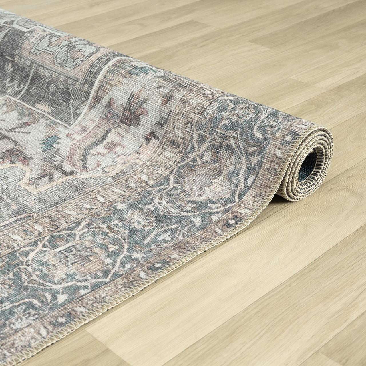 Rolled grey runner rug with distressed floral traditional patterns on light wood floor.