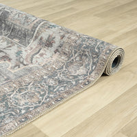 Rolled grey runner rug with distressed floral traditional patterns on light wood floor.