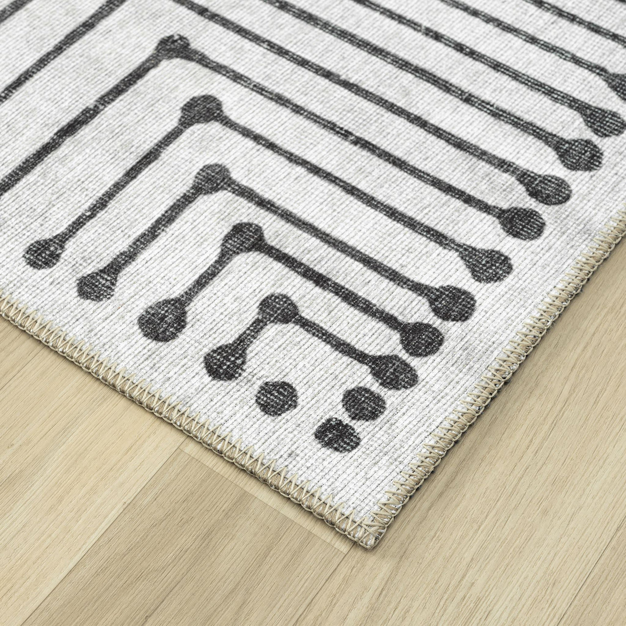 Black and white geometric patterned flatweave runner rug on light wood floor.