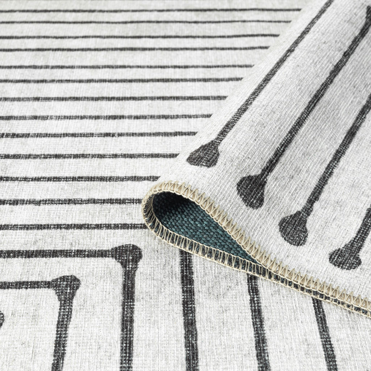 Black and white geometric patterned flatweave runner rug with linear and dot motifs on cream background.