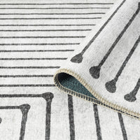 Black and white geometric patterned flatweave runner rug with linear and dot motifs on cream background.