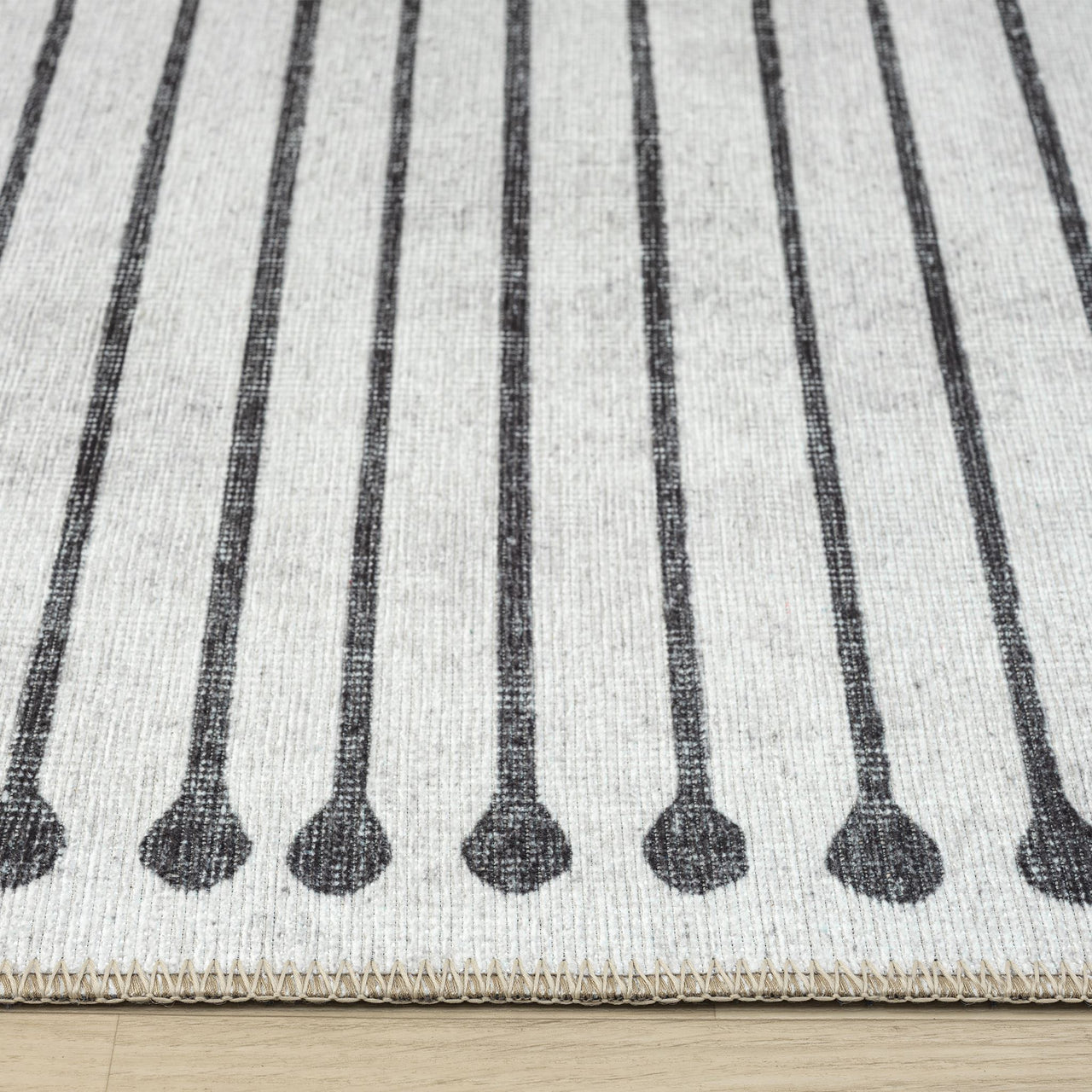 Black and white geometric patterned runner rug with vertical lines and rounded ends on flat-weave texture.