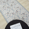 Traditional runner rug with muted blue, beige, and pink floral tree pattern on cream background.