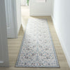 Traditional runner rug with light blue, beige, and gray floral tree pattern on a cream background.