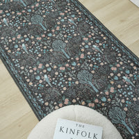 Grey traditional runner rug with multi-coloured floral pattern and subtle blue border on light wood floor.