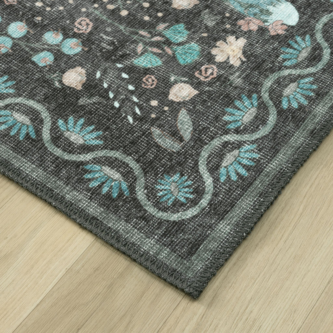 Grey flatweave runner rug with teal, pink, and cream floral motifs and curved border design.