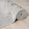 Rolled-up gray textured rug on a wooden floor