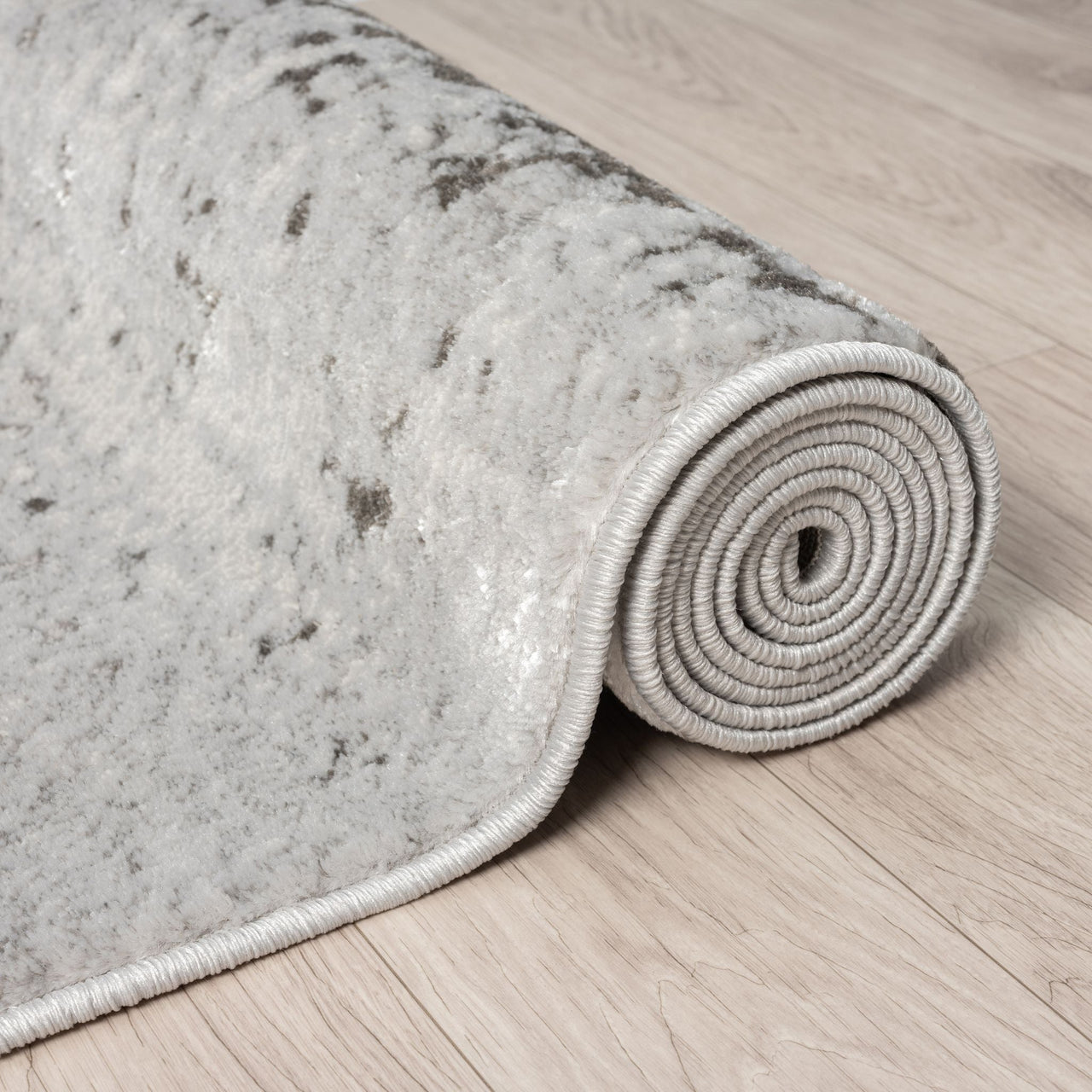 Rolled-up gray textured rug on a wooden floor