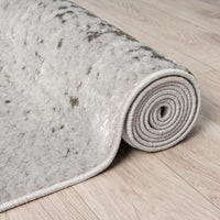 Rolled-up gray textured rug on a wooden floor