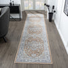 Indigo runner rug with intricate modern floral and geometric patterns in soft blue, beige, and brown tones on hardwood floor.