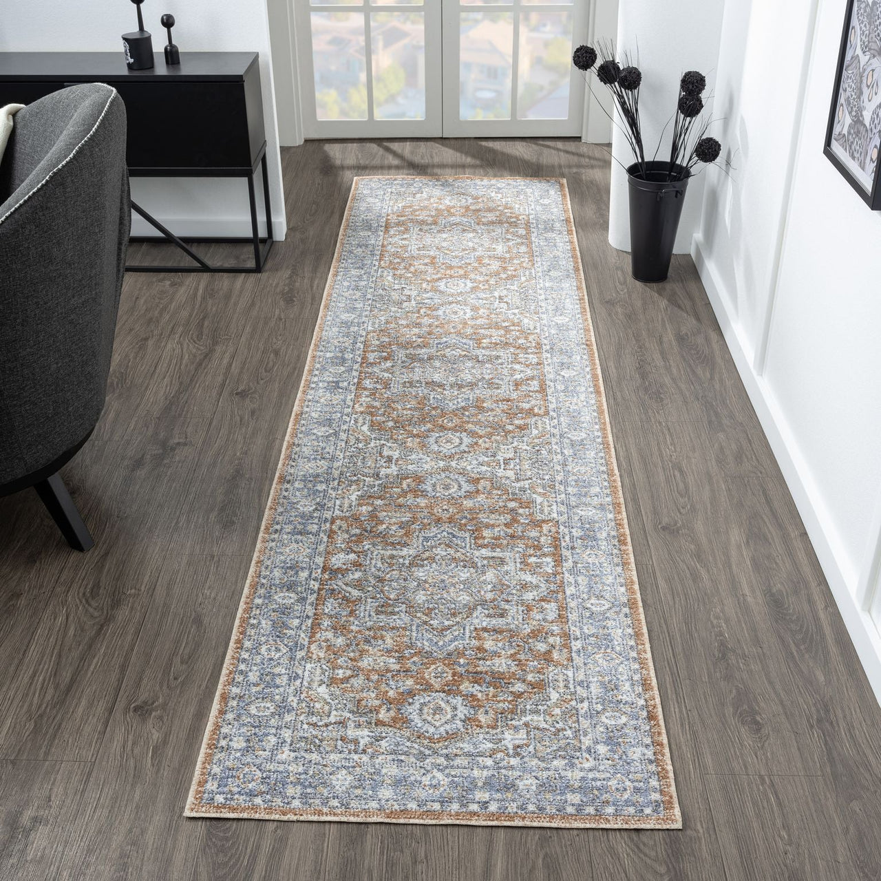 Indigo runner rug with intricate modern floral and geometric patterns in soft blue, beige, and brown tones on hardwood floor.