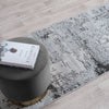 Gray rug with a textured pattern on a wooden floor, featuring a book titled 'The Kinfolk Table' on a gray stool.