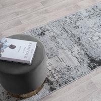 Gray rug with a textured pattern on a wooden floor, featuring a book titled 'The Kinfolk Table' on a gray stool.