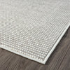 Close-up of grey flatweave rug with textured geometric pattern and clean edge on wood floor.