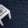Navy blue modern shaggy rug with dense polyester pile under white table corner.